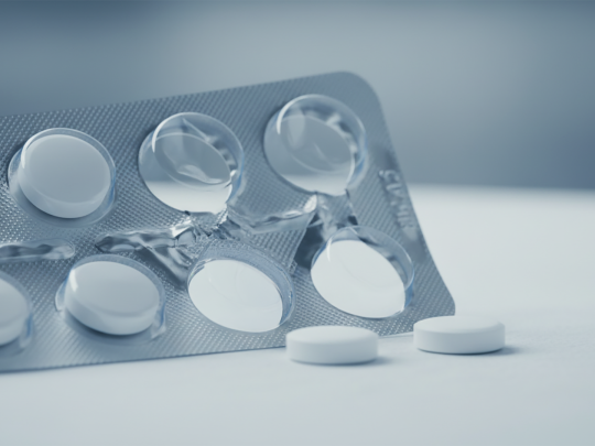 Nahaufnahme eines teilentleerten Tabletten-Blisters mit wei&szlig;en, runden Arzneitabletten auf einer sauberen Laboroberfl&auml;che. Das k&uuml;hle, klinische Setting unterstreicht Qualit&auml;tssicherung, GMP-konforme Analytik und zuverl&auml;ssige Freigabepr&uuml;fungen f&uuml;r Pharma- und Biotech-Hersteller in regulierten M&auml;rkten.
